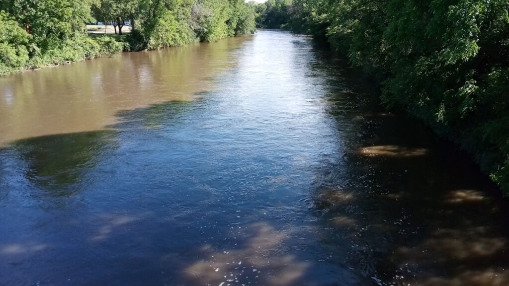 Trail crossing very high brown and blue water of Cannon River